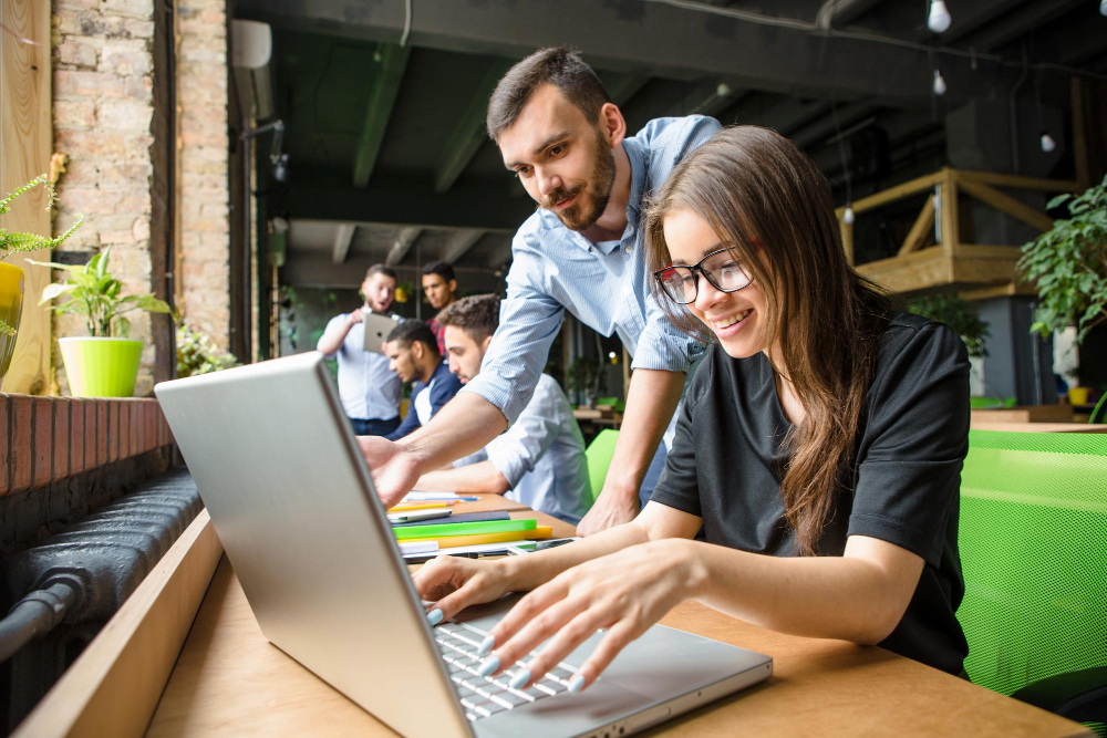 Mujer sonriendo mientras trabaja en un laptop en un espacio creativo